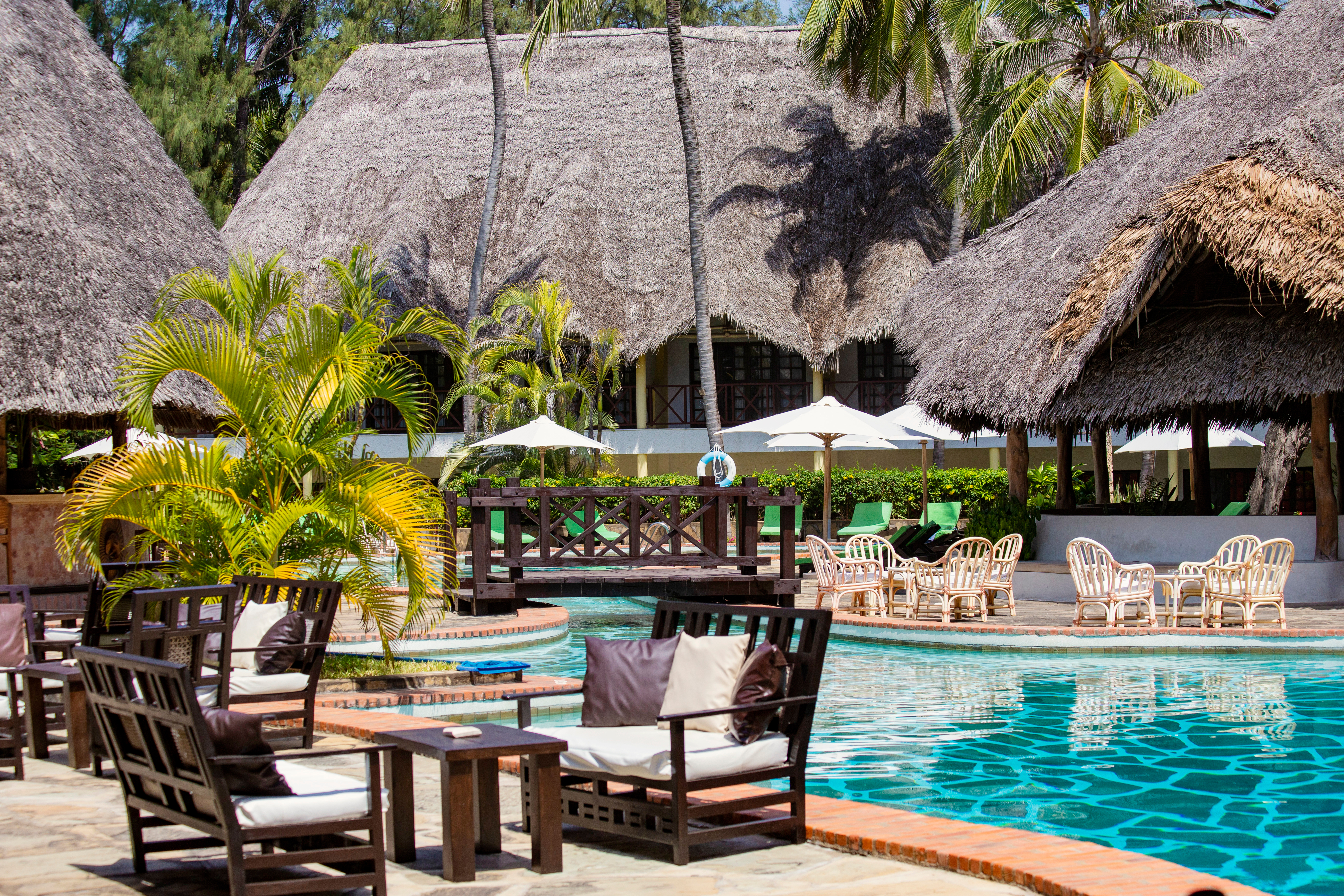 Thatched-roof resort with sun loungers beside a pool